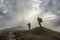 Hikers take photos on the top of a mountain with clouds around a