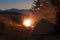 Hikers tent in mountains at evening with a bonfire with sparkles