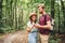 Hikers using mobile gps for directions. Happy couple checking smartphone in the woods during backpacking trip. Young joyful couple