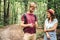 Hikers using mobile gps for directions. Happy couple checking smartphone in the woods during backpacking trip. Young joyful couple