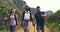 Hikers walking down a trail on a mountain with hiking sticks. Diverse group of active and adventurous young friends