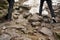 Hikers walking in forest, detail on their boots / shoes stepping over wet rocks, some of them still covered with snow