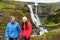 Hiking active couple fun by waterfall Iceland
