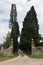 Hiking backroads of Tuscany, resting in shadow of cypress trees at villa entrance, near Siena