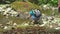 Hiking beautiful woman with backpack squatting and making photo by smartphone on mountain river with large boulders and