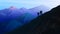 Hiking and camping concept. Silhouette of tourists climbing to the top of the Swiss or Austrian Alps. Dark blue