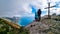 Hiking couple with backpack at  summit cross near Santa Maria del Castello with scenic view on Positano Amalfi Coast, Italy