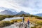 Hiking couple walking on adventure hike at Routeburn Track during sunny day. Hikers carrying backpacks tramping on Key