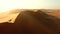 Hiking, exploring and adventure with a man walking on a sand dune in a hot, arid and barren desert landscape. Drone of a