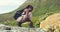 Hiking female mountain climber tying her shoelaces before jumping away on rocks and boulders. Fit young african woman on