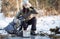 Hiking: A girl with a backpack in a winter forest stopped at an ice hole to collect and drink water.