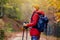 Hiking girl with poles and backpack on a trail. Looking at camera. Travel and healthy lifestyle outdoors in fall season