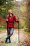 Hiking girl with poles and backpack on a trail. Looking at camera. Travel and healthy lifestyle outdoors in fall season