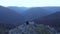 Hiking group of friends relaxing on a mountain cliff. Aerial slow motion view