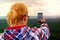 Hiking long hair blonde woman taking photo with smart phone at mountains.