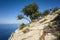 Hiking on Lycian way. Man with backpack walking down on steep rock slope high above Mediterranean sea on Lycian Way
