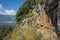 Hiking Lycian way. Man is descending tricky path on cliff high above Mediterranean sea near ancient rock tomb of Saba