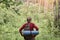 Hiking. Man wearing red sweater and cap in hike, having backpack and sleeping pad, looking towards. Sporty man hiking on green