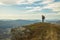 Hiking mountain top edge of cliff highland scenic view with backpacker male person stay and looking side ways life style poster