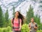 Hiking people walking on mountain trail landscape. Happy hikers h in outdoor nature looking up on green pine trees