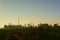 Hiking trail through farm landscape with silhouette of radio tower and watchtowers of an airport in evening light