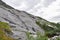 Hiking trail to Tvillingene peak going upwards a grey stone mountain slope covered by grass and moss