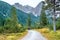 Hiking trip, Dolomites landscape. Pair of tourists is walking along a wide trail in the Dolomites. The Tofane Group in the