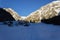 Hiking in winter. Afternoon shadows darken the highland. Mountains in the background are still sunny.