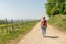 Hiking Woman with brown hair, straw hat and backpack hiking next to a wine field on a hiking trail