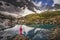 Hiking woman in red jacket stay at beautiful reflection of a lake in mountains.