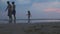 HIKKADUWA, SRI LANKA - FEBRUARY 2014: The View of Hikkaduwa beach at sunset with family of three running by. Hikkaduwa is famous