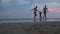 HIKKADUWA, SRI LANKA - FEBRUARY 2014: The View of Hikkaduwa beach at sunset with family of three running by. Hikkaduwa is famous