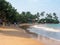 Hikkaduwa, Sri Lanka - March 4, 2022: Beautiful view of the beach in Hikkaduwa with bright green palm trees. People walk, relax