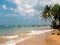 Hikkaduwa, Sri Lanka - March 8, 2022: Beautiful view of Hikkaduwa beach with green palm trees. Boats stand along the coast of the