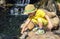 Ð¡hild kid boy 3 year in straw hat and a yellow T-shirt, touches his hand to the water in the pond. Vacations and Walking in zoo