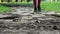Ð¡hild legs walking towards the camera on the wooden pathway. Girl in black shoes walks in park.