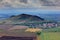 Hill with clouds. Beautiful morning landscape. Village below the hill. Landscape with fields and meadow around mound. Sky before