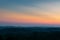 Hill layers separated with haze and vibrant glow in sky above horizon at twilight