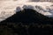 hill with pine trees under iridescent clouds