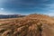 Hill with red grass and rocks with deep blue sky