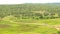 A hill view of agricultural fields with small village road.