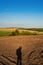 Hills are agricultural land, plowed land with shadows silouette man on the ground