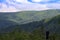 Hills in Polish mountains, you can see growing tall trees and blue sky.