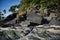 Hillside with black rocks and green trees, plants on the shores of the sandy beautiful exotic and stunning Cenang beach in