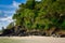 Hillside with black rocks and green trees, plants on the shores of the sandy beautiful exotic and stunning Cenang beach in