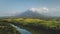 Hillside river at erupt volcano: green grass shore at Philippines countryside aerial. Fields, valley