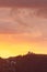 Hillside view of homes, ovservatory and palms silhoutted against lavender, pink, orange, and yellow