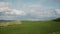 Hilly green meadow with dreamy clouds and blue sky. Tuscan landscape of serenity