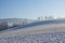 Hilly landscape in winter with a tall electricity pylon leading high electric current in the background