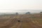 Hilly rural landscape. Harvested wheat field with straw bales and fog filled valley in early morning